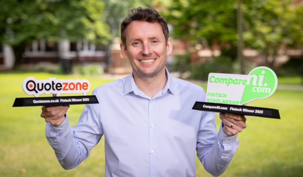 Seopa Ltd. Managing Director Ian Wilson holding two Fintech Scholarship trophies, one for Quotezone and one for CompareNI - generic scenic background with grass and trees visible.